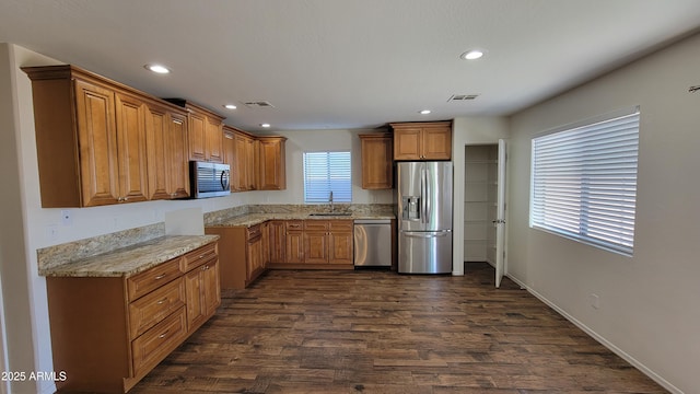 kitchen featuring visible vents, a sink, brown cabinets, appliances with stainless steel finishes, and dark wood-style floors