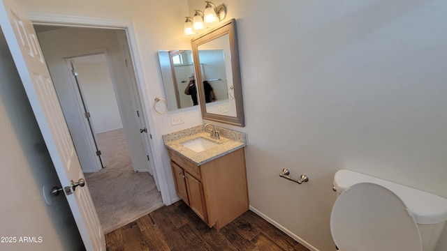 bathroom featuring baseboards, vanity, toilet, and wood finished floors