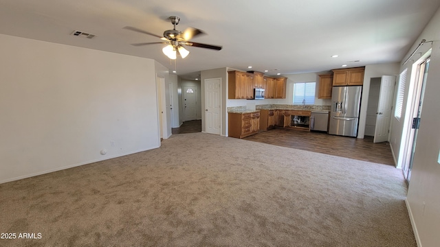 kitchen featuring baseboards, visible vents, brown cabinets, dark carpet, and appliances with stainless steel finishes