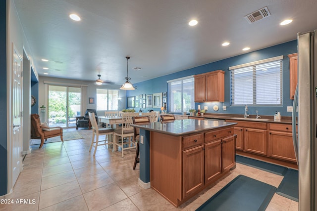 kitchen with dark countertops, visible vents, freestanding refrigerator, open floor plan, and a sink