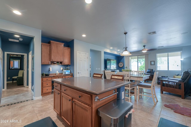 kitchen featuring a kitchen island, visible vents, open floor plan, brown cabinets, and dark countertops