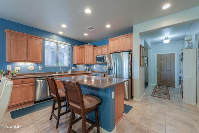 kitchen featuring visible vents, dark countertops, a kitchen island, a breakfast bar area, and stainless steel appliances