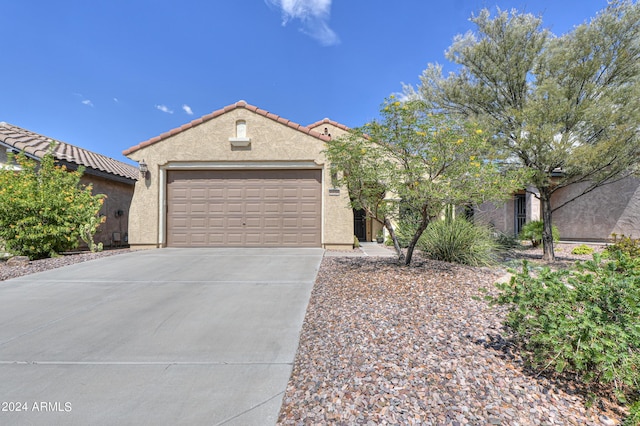 mediterranean / spanish home with a garage, driveway, a tiled roof, and stucco siding