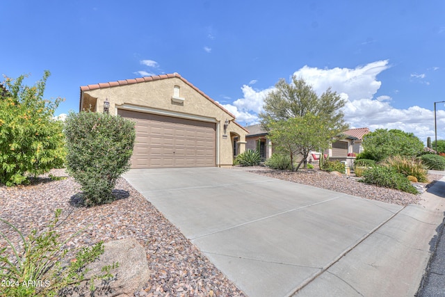 view of front of home featuring concrete driveway, an attached garage, a tiled roof, and stucco siding