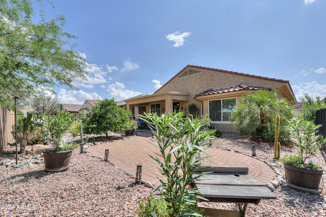 back of property featuring stucco siding, a tiled roof, fence, and a patio