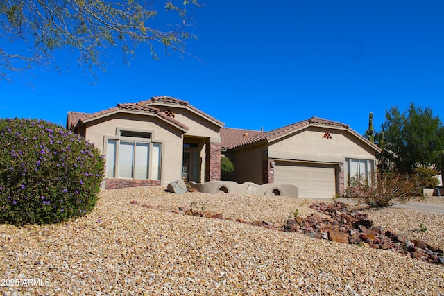 mediterranean / spanish-style home with stone siding, an attached garage, a tiled roof, and stucco siding