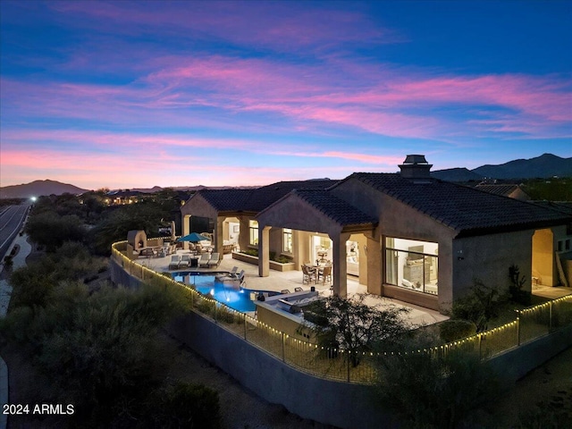 back house at dusk featuring a mountain view, outdoor lounge area, a fenced in pool, and a patio area