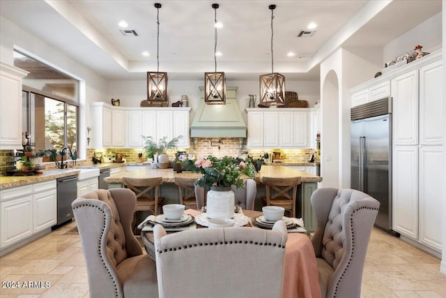 kitchen featuring decorative light fixtures, stainless steel appliances, white cabinets, and decorative backsplash