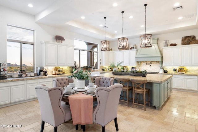 kitchen with a center island, tasteful backsplash, white cabinetry, a raised ceiling, and decorative light fixtures