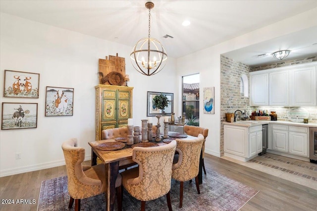 dining space featuring an inviting chandelier, wine cooler, light hardwood / wood-style floors, and sink