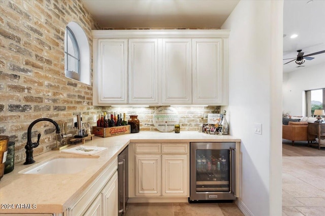 kitchen featuring beverage cooler, ceiling fan, sink, and brick wall