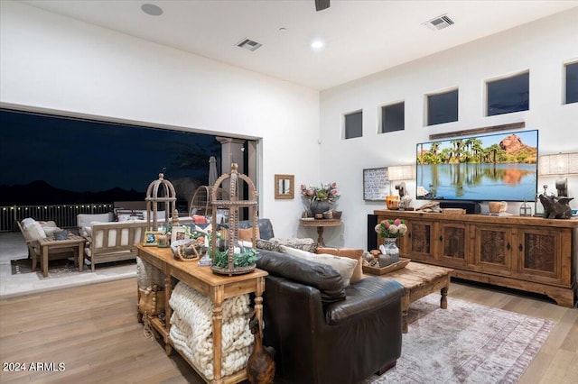 living room featuring a towering ceiling and light hardwood / wood-style flooring