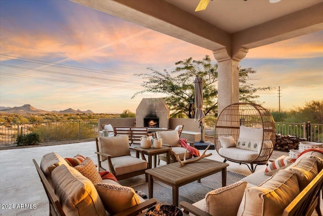 patio terrace at dusk with an outdoor living space with a fireplace and a mountain view