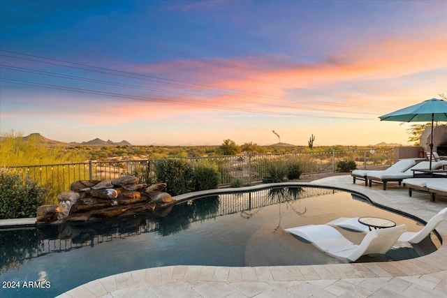 pool at dusk with a patio area