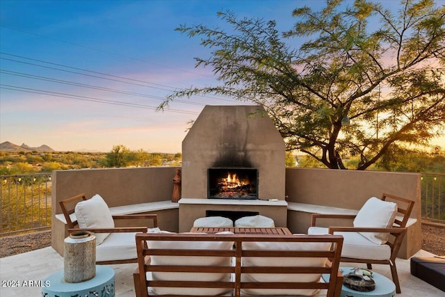 patio terrace at dusk featuring an outdoor fireplace