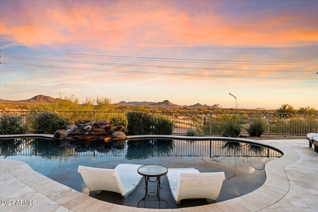 pool at dusk featuring a patio and a mountain view