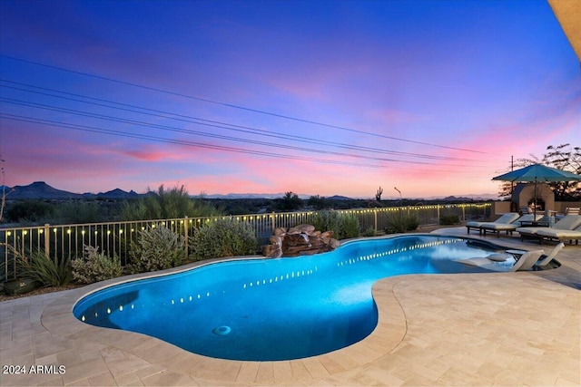 pool at dusk featuring a patio