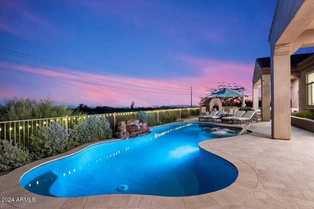 pool at dusk with a patio area