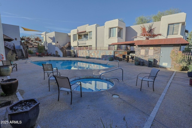 community pool featuring a patio, stairway, and a hot tub