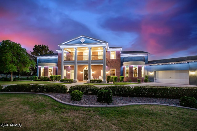 neoclassical home featuring a balcony, a garage, and a lawn