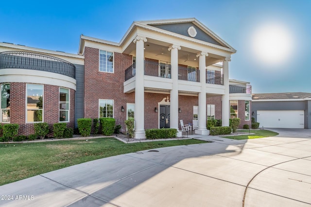 greek revival inspired property featuring a balcony, a garage, and a front lawn