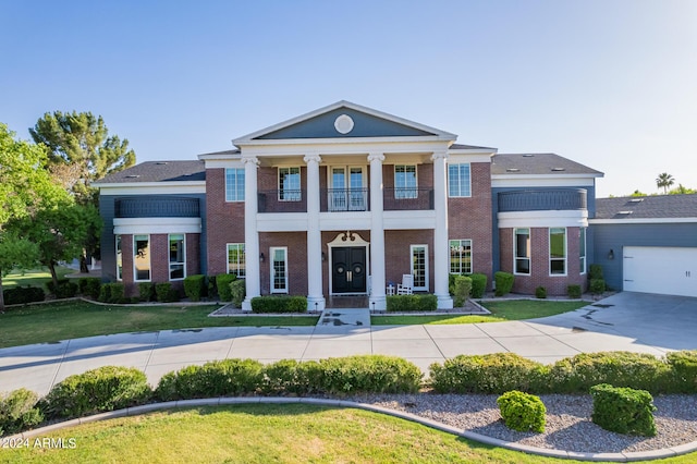 neoclassical home with a garage and a front lawn