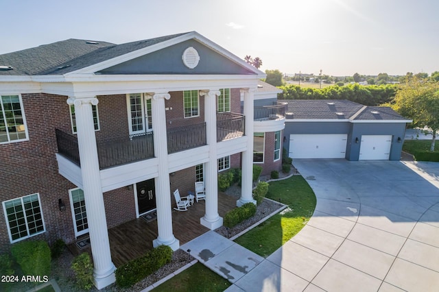 neoclassical / greek revival house featuring a balcony, covered porch, and a garage