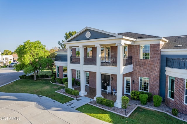 neoclassical / greek revival house with a porch, a balcony, and a front lawn