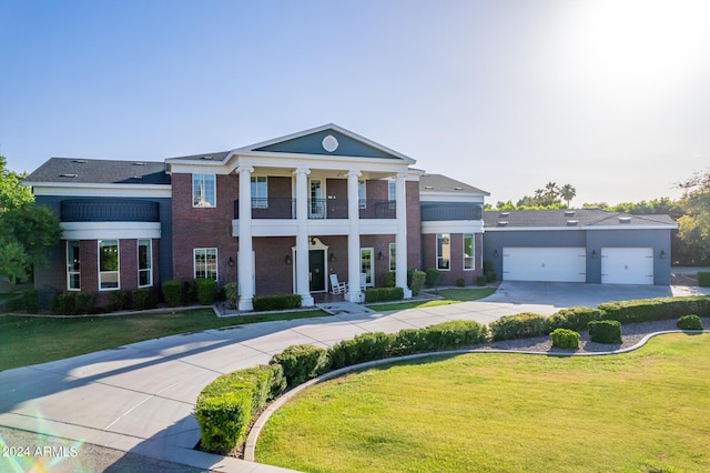 greek revival inspired property featuring a garage, a balcony, and a front yard