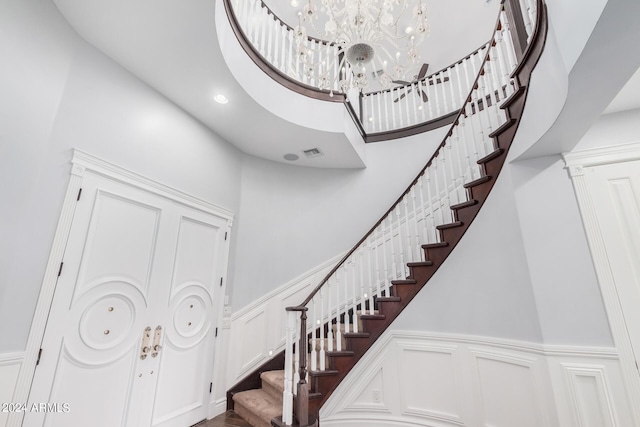 stairs with a notable chandelier and a high ceiling