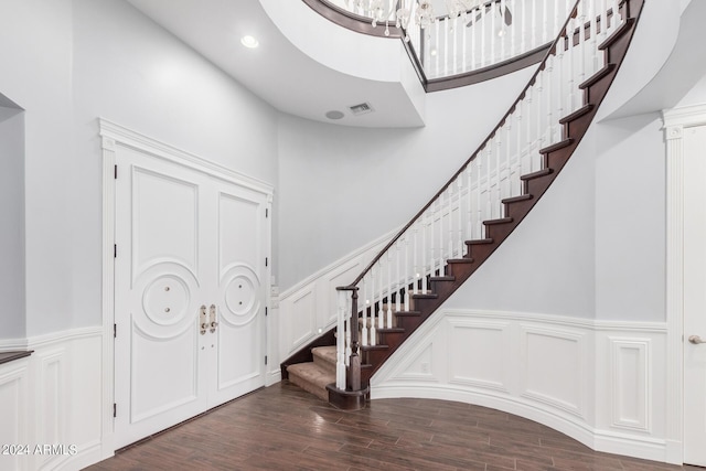 entrance foyer with a towering ceiling, dark hardwood / wood-style floors, and a notable chandelier