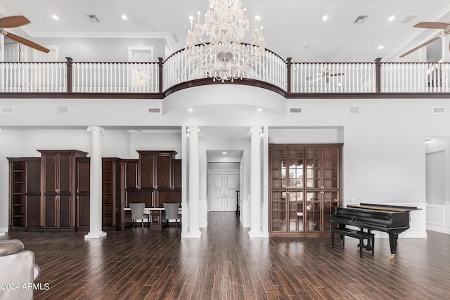 interior space featuring dark hardwood / wood-style floors, ceiling fan, ornate columns, and a high ceiling