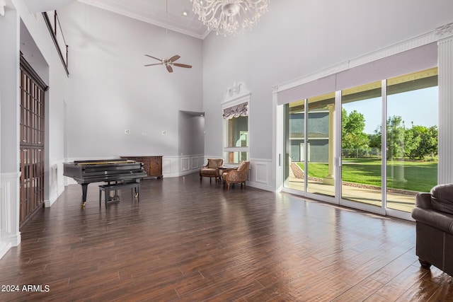 miscellaneous room with ceiling fan with notable chandelier, a towering ceiling, and dark wood-type flooring