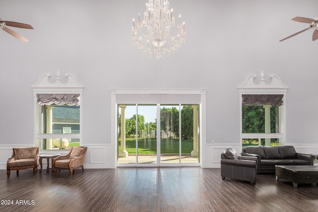 living room featuring a high ceiling, ceiling fan with notable chandelier, dark hardwood / wood-style floors, and plenty of natural light