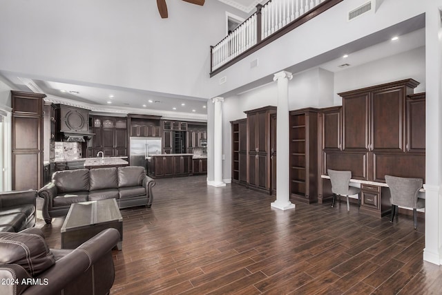 living room featuring dark hardwood / wood-style flooring, ornate columns, and a high ceiling