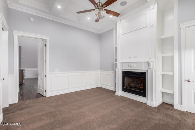 unfurnished living room with built in shelves, ceiling fan, ornamental molding, and dark colored carpet