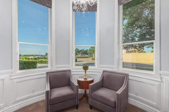 sitting room featuring plenty of natural light, carpet, and an inviting chandelier