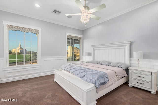 carpeted bedroom with ceiling fan, crown molding, and multiple windows