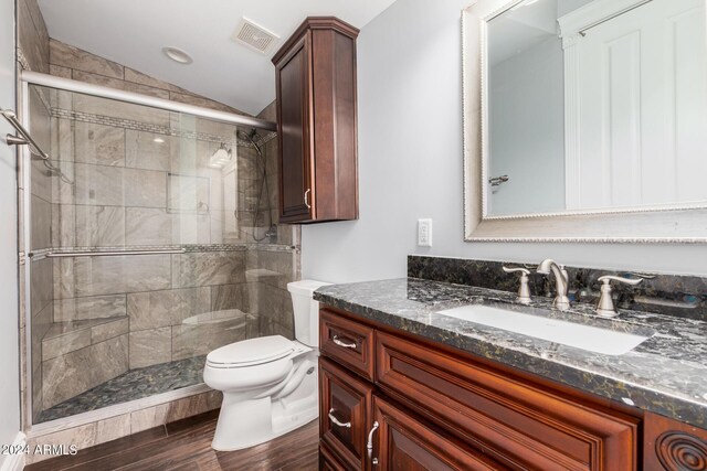 bathroom featuring vanity, vaulted ceiling, hardwood / wood-style flooring, toilet, and a shower with shower door