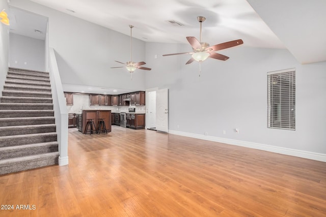 living room with light hardwood / wood-style floors, high vaulted ceiling, and ceiling fan