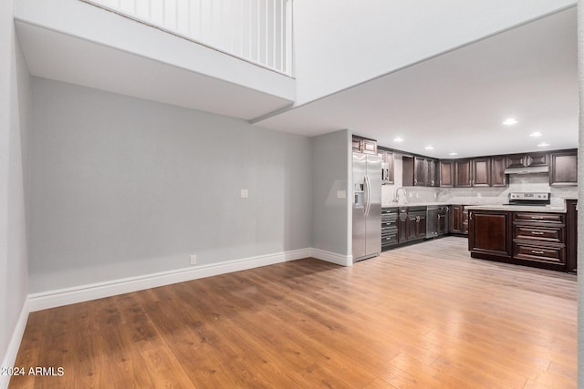 kitchen with light hardwood / wood-style floors, stainless steel fridge, dark brown cabinetry, and tasteful backsplash