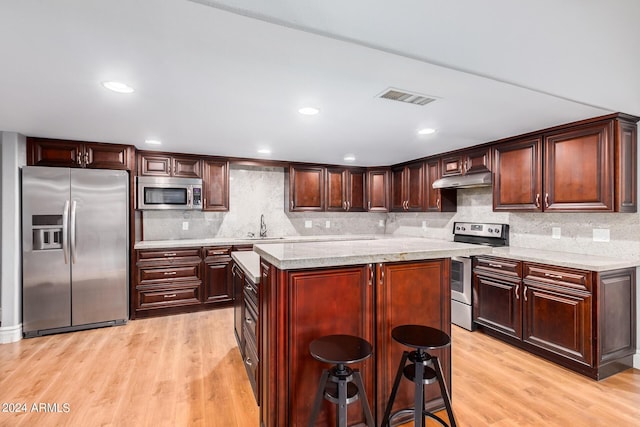 kitchen featuring light hardwood / wood-style floors, stainless steel appliances, and tasteful backsplash