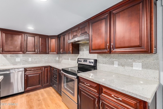 kitchen featuring light stone countertops, backsplash, stainless steel appliances, and light hardwood / wood-style flooring