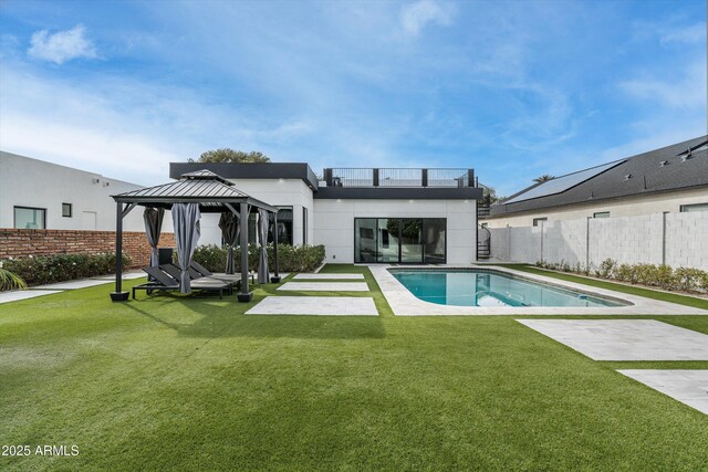 back of house featuring fence, a gazebo, a lawn, a fenced in pool, and a patio area