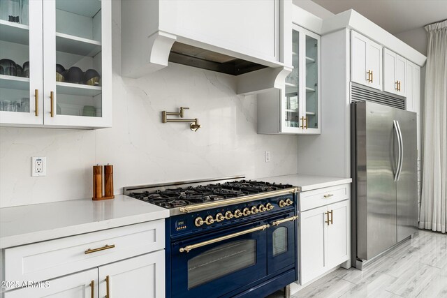 kitchen with tasteful backsplash, double oven range, stainless steel fridge, and white cabinetry