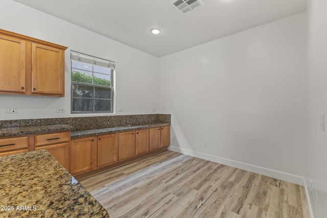 kitchen featuring baseboards, light wood-style flooring, visible vents, and brown cabinets