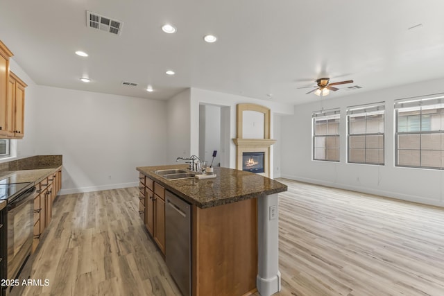 kitchen featuring visible vents, a kitchen island with sink, stainless steel dishwasher, black range with electric cooktop, and a sink