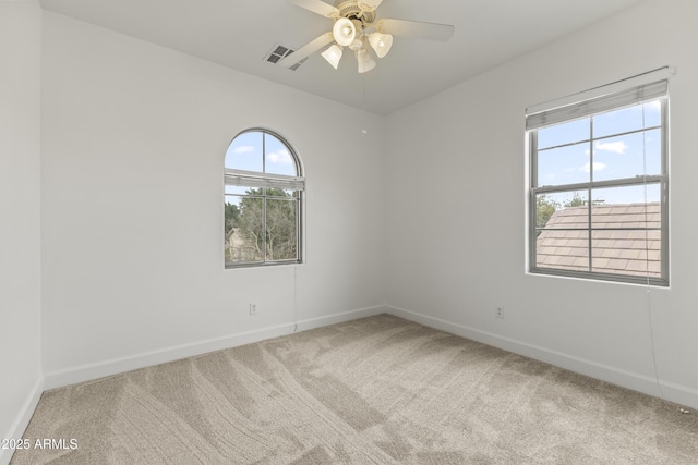 carpeted spare room with baseboards, visible vents, and a ceiling fan