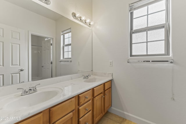 full bathroom with double vanity, tile patterned flooring, baseboards, and a sink