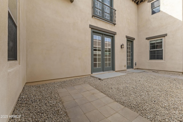 entrance to property with stucco siding, french doors, and a patio